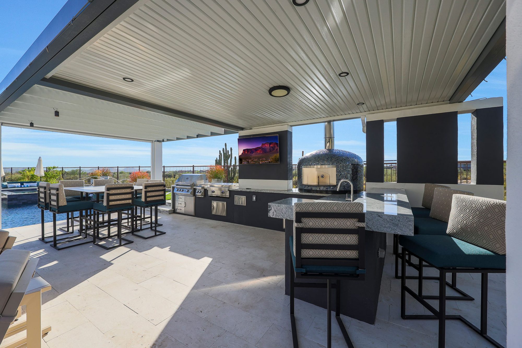 Covered outdoor kitchen with motorized shade and dining bar
